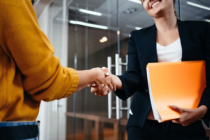 shaking hands in office holding orange folder
