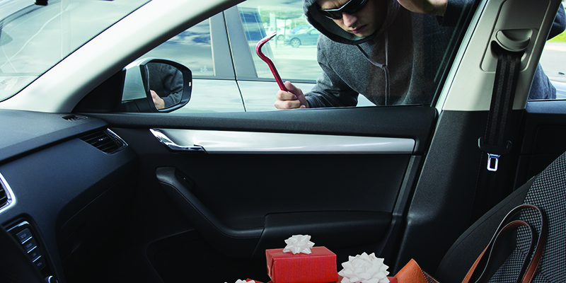 Thief with crowbar in car window looking at present in front seat