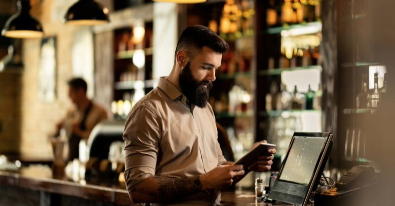Young bartender using a digital tablet while working at a pub