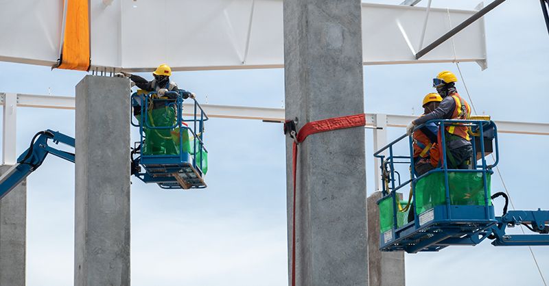 Construction workers working at boom lift installation steel roof beam