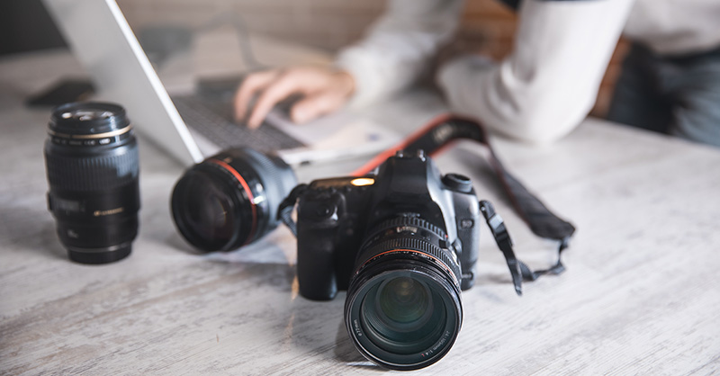 Man sitting at laptop with camera gear