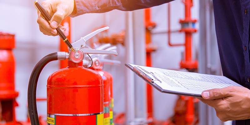 Man checking fire extinguisher during a fire safety assessment