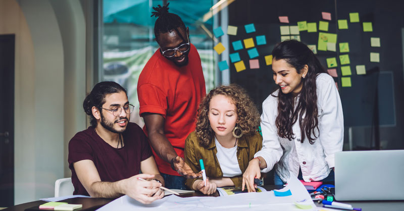 Young adults in meeting looking at papers on a table