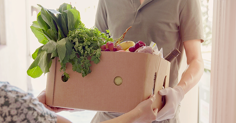Man with Gloves Holding Box of Food for Donating