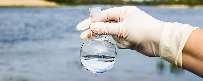 Hand holding water test tube with lake in the background