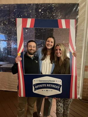 3 people posing for a photo with a frame prop