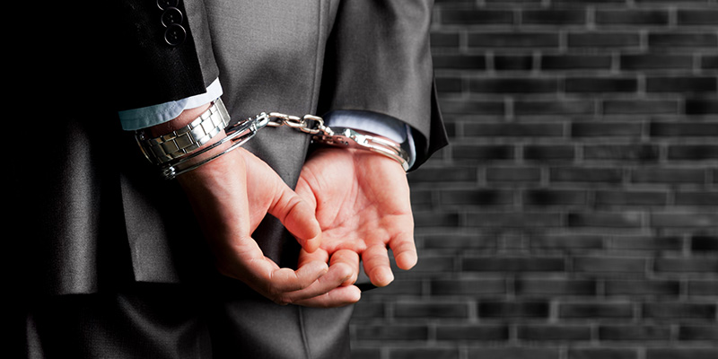 Man wearing business suit in handcuffs