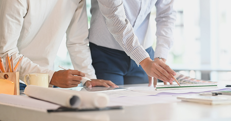 Two architects working in office with blueprints