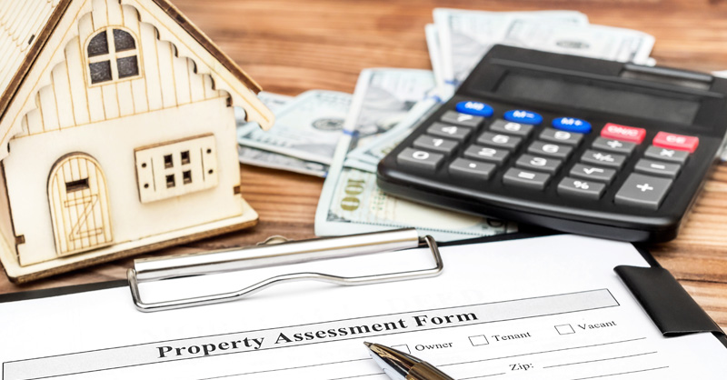 Toy house next to clipboard with Property Assessment Form and calculator