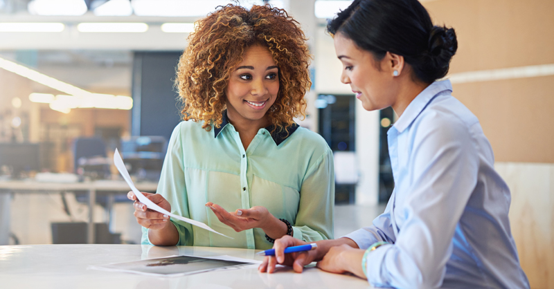 Two smiling women looking at paperwork